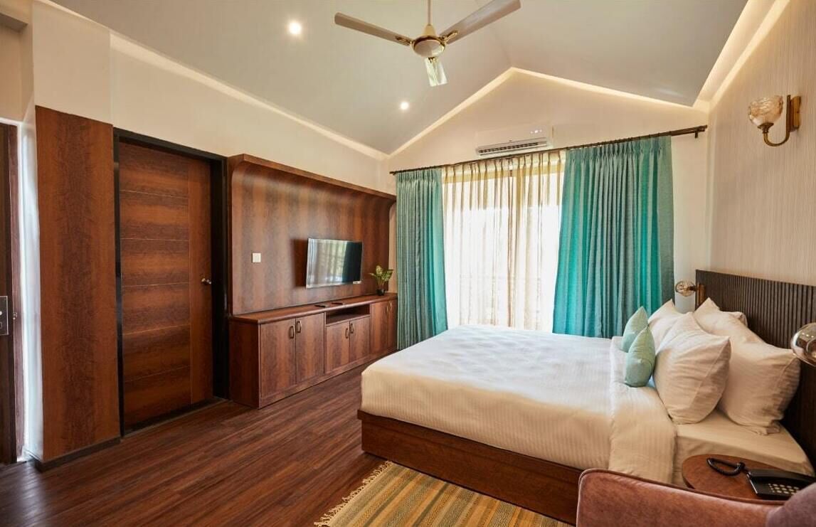 Um quarto com uma cama, televisão, guarda-roupa e ventoinha no teto.