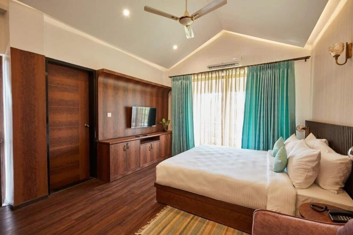Um quarto com uma cama, televisão, guarda-roupa e ventoinha no teto.