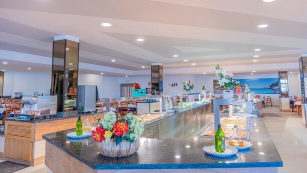 A modern hotel lobby with a buffet area, seating, and a view of the sea. - Club Cala Romani (Manacor)