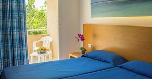 Ein Hotelzimmer mit einem Bett, einem kleinen Tisch mit Früchten, einem Sessel und einem Bild an der Wand.