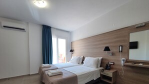 A hotel room with a bed, bedside table, lamp, phone, and a mirror. - Elounda Sunrise Apartments (Agios Nikolaos)