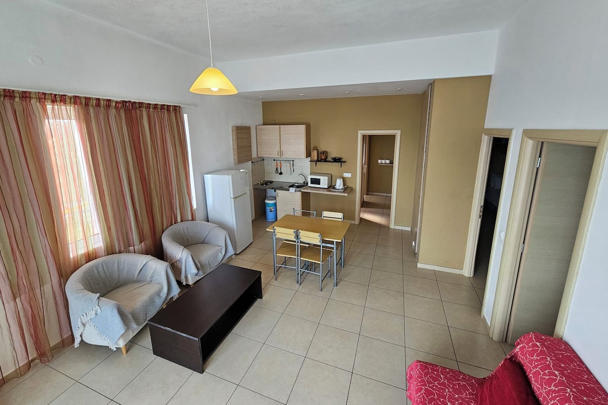 A compact living space with a kitchenette, a dining area, and a seating area with a sofa and armchair.