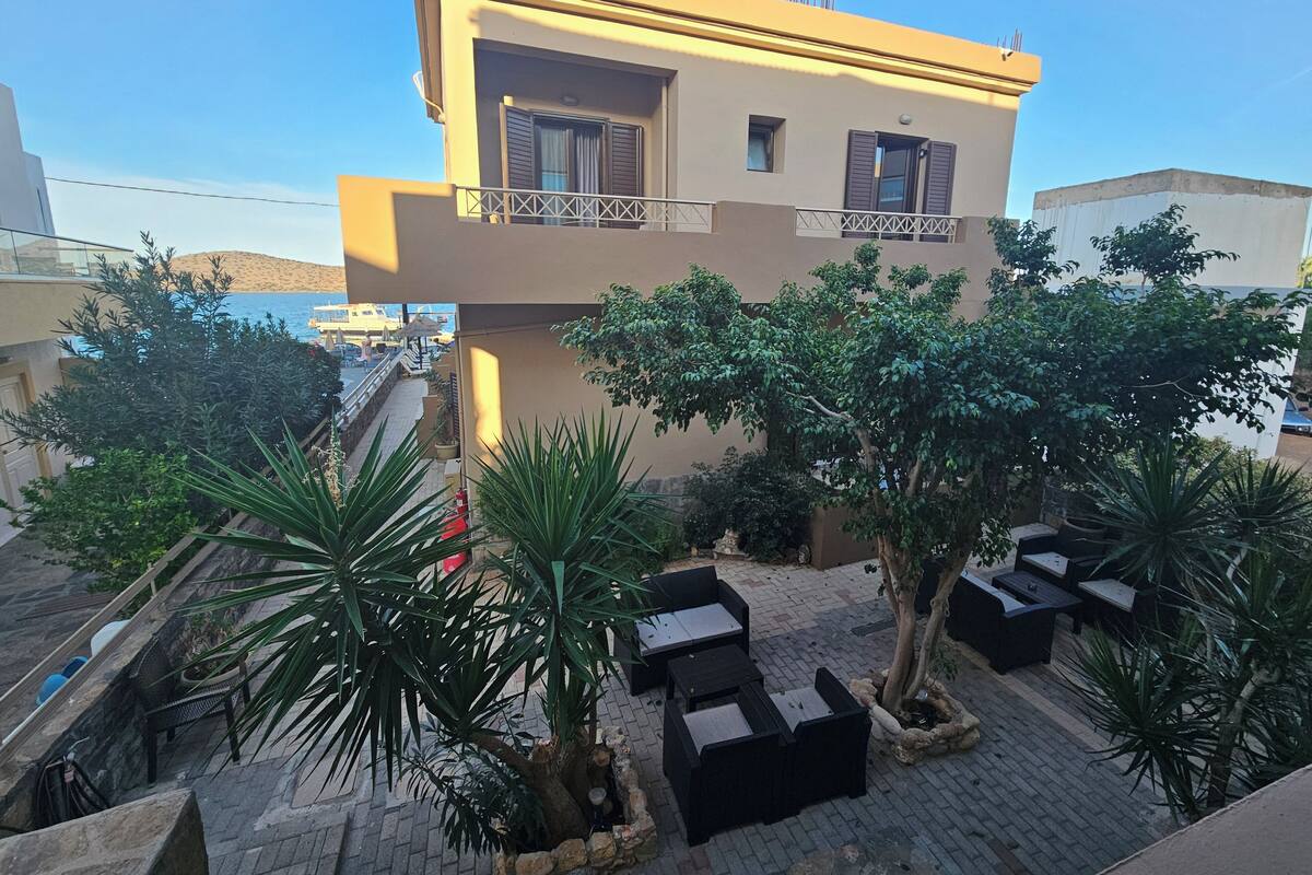 A building with a balcony, potted plants, and outdoor furniture.