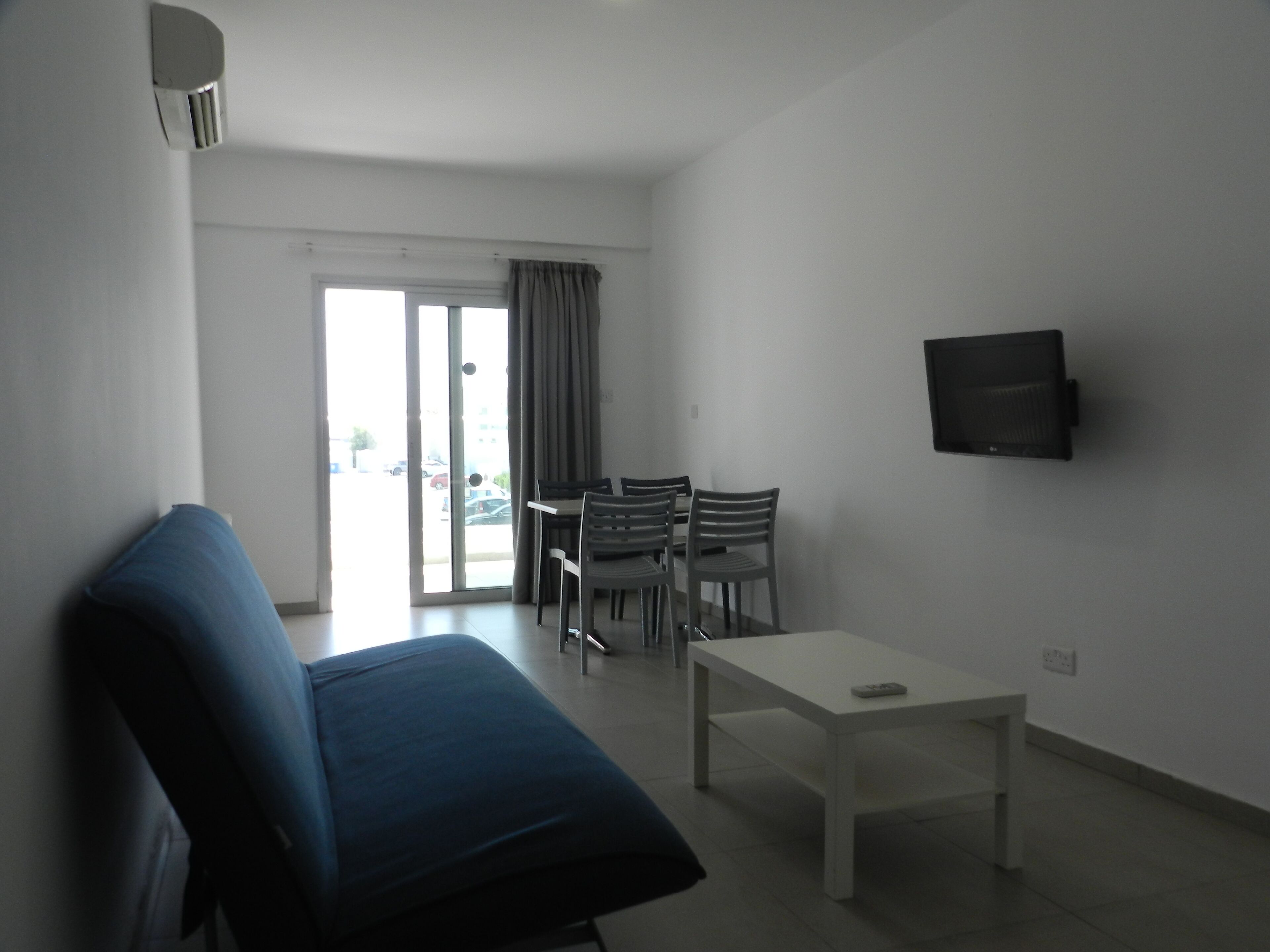 Una habitación con una cama, una mesa y un televisor en la pared.