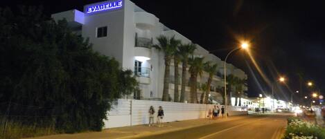 A white building with a 'SABELLIE' sign, palm trees, and a street with people.