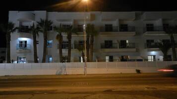 A multi-story building with balconies, palm trees, and a streetlight.
