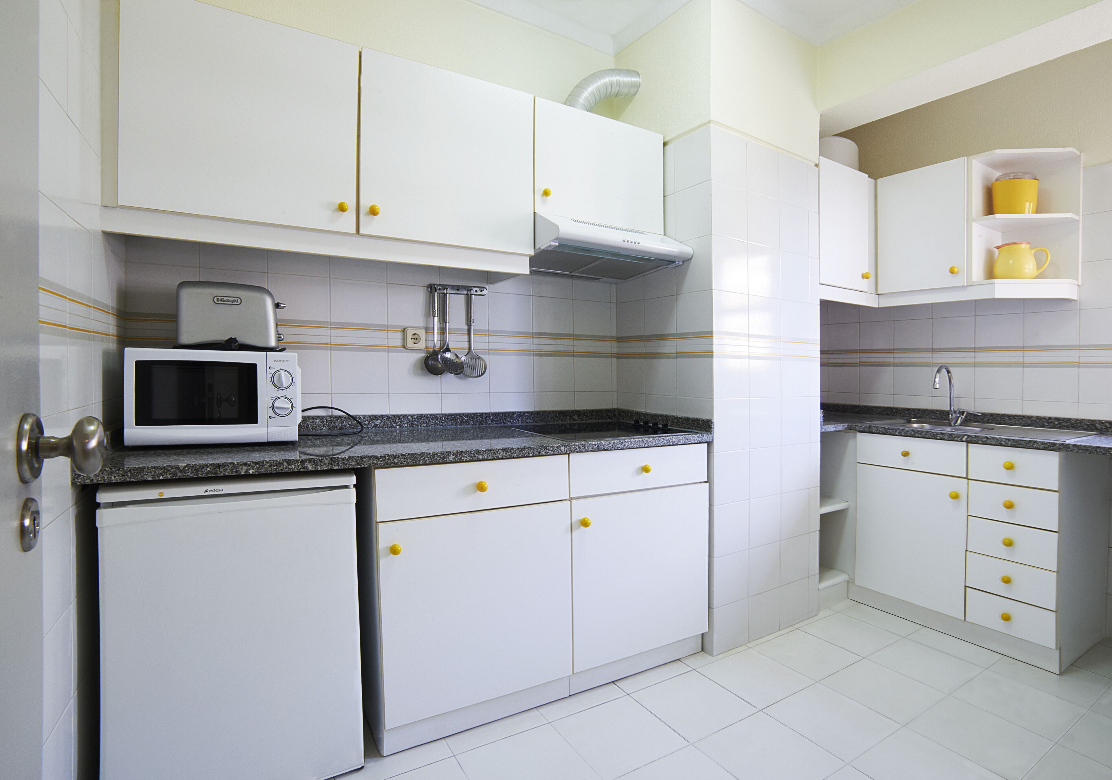 A kitchen with white cabinets, a microwave, and a sink.