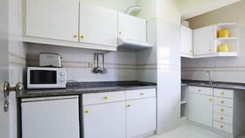 A kitchen with white cabinets, a microwave, and a sink.