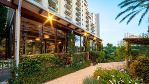 A hotel with a covered outdoor area, a paved walkway, and lush greenery. - RR Club  Amarilis (Portimão)