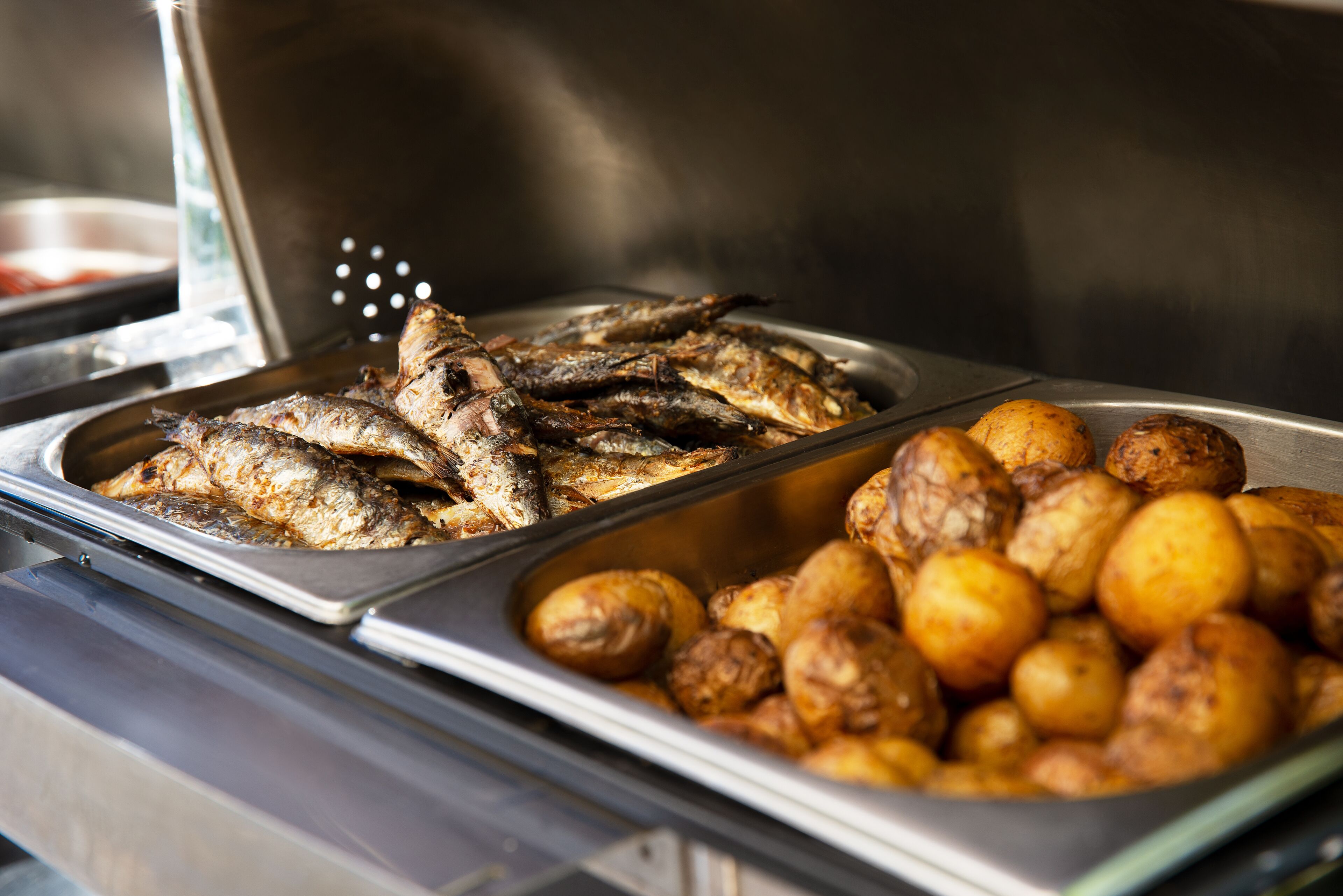 A buffet with roasted fish and potatoes.