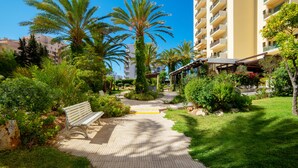 A pathway leading to a building with balconies, surrounded by palm trees and greenery. - RR Club  Amarilis (Portimão)
