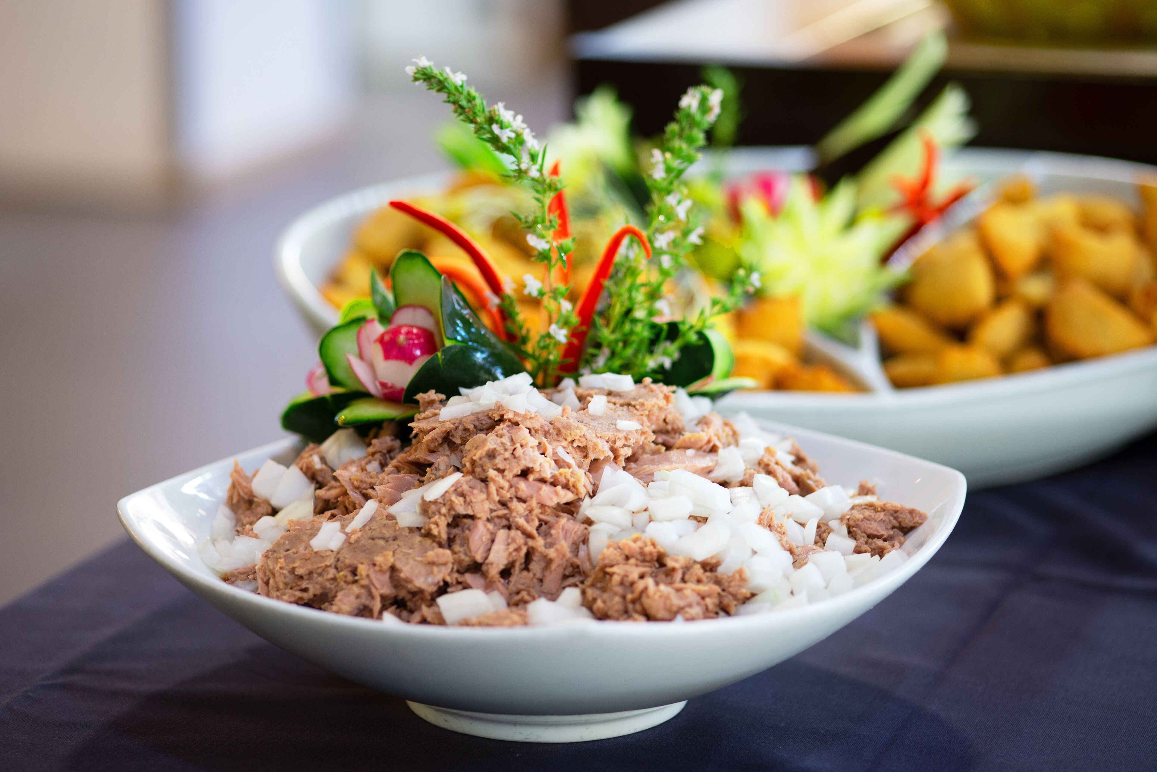 Une salade de thon aux légumes, servie dans un bol et agrémentée d’une garniture décorative.