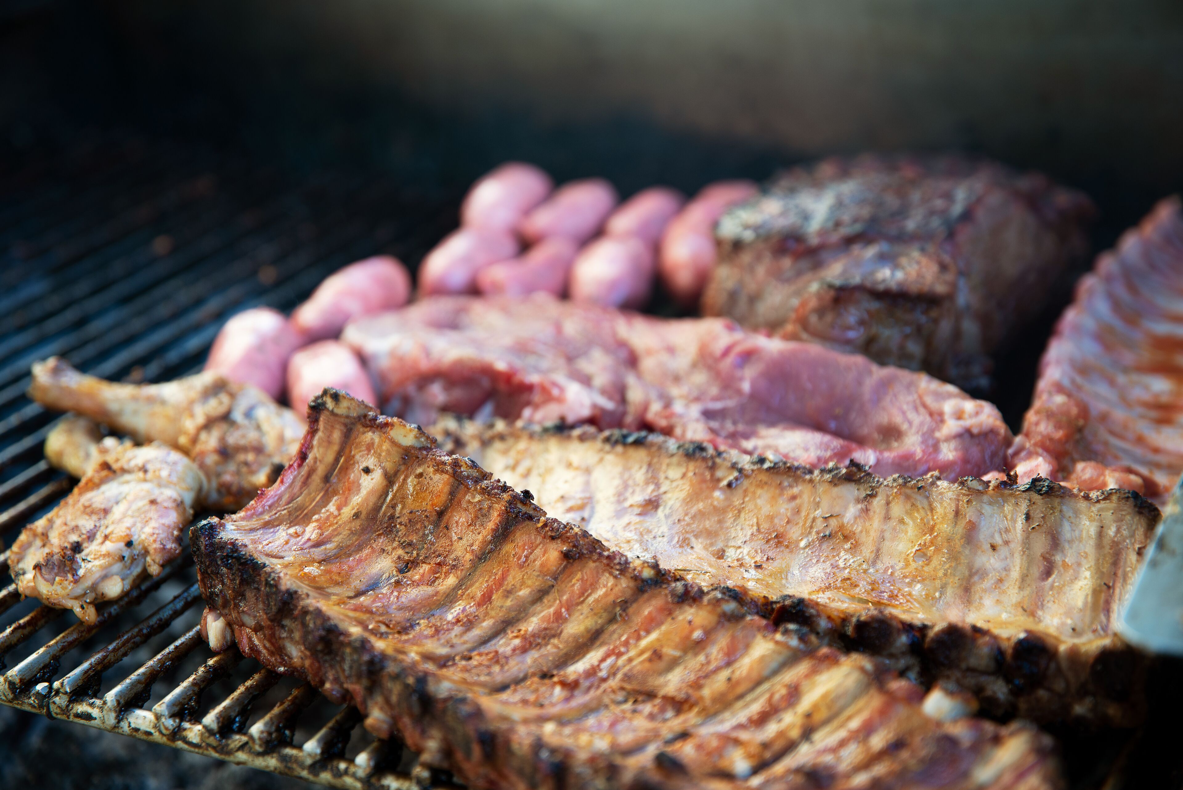 A grill with various meats, including ribs and sausages.