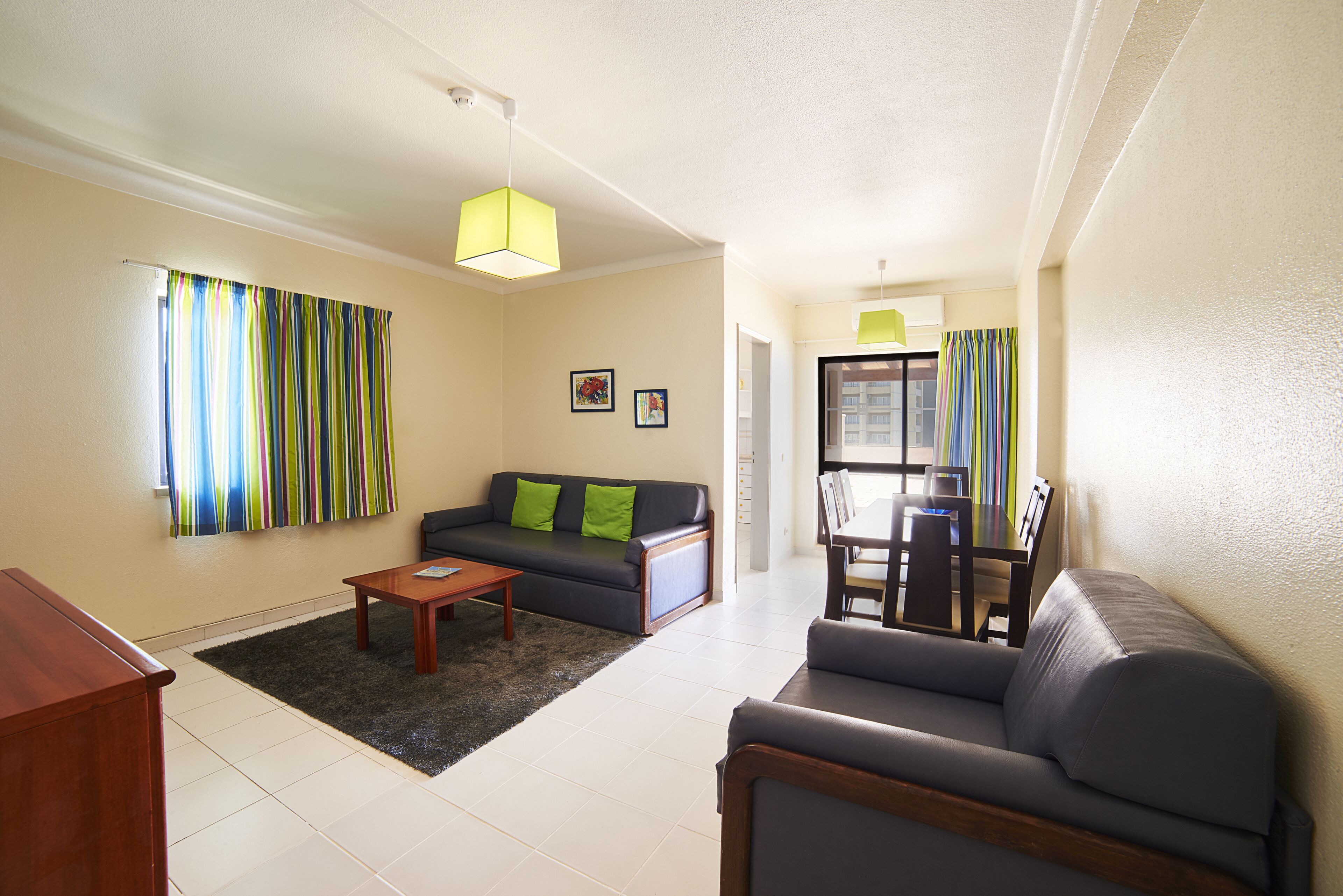 A living room with a sofa, a coffee table, and a dining area with chairs and a table.