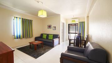 A living room with a sofa, a coffee table, and a dining area with chairs and a table.