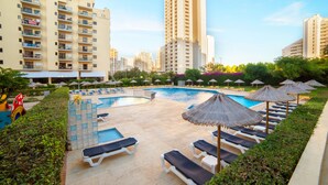 A hotel pool area with sun loungers and umbrellas, surrounded by high-rise buildings. - RR Club  Amarilis (Portimão)