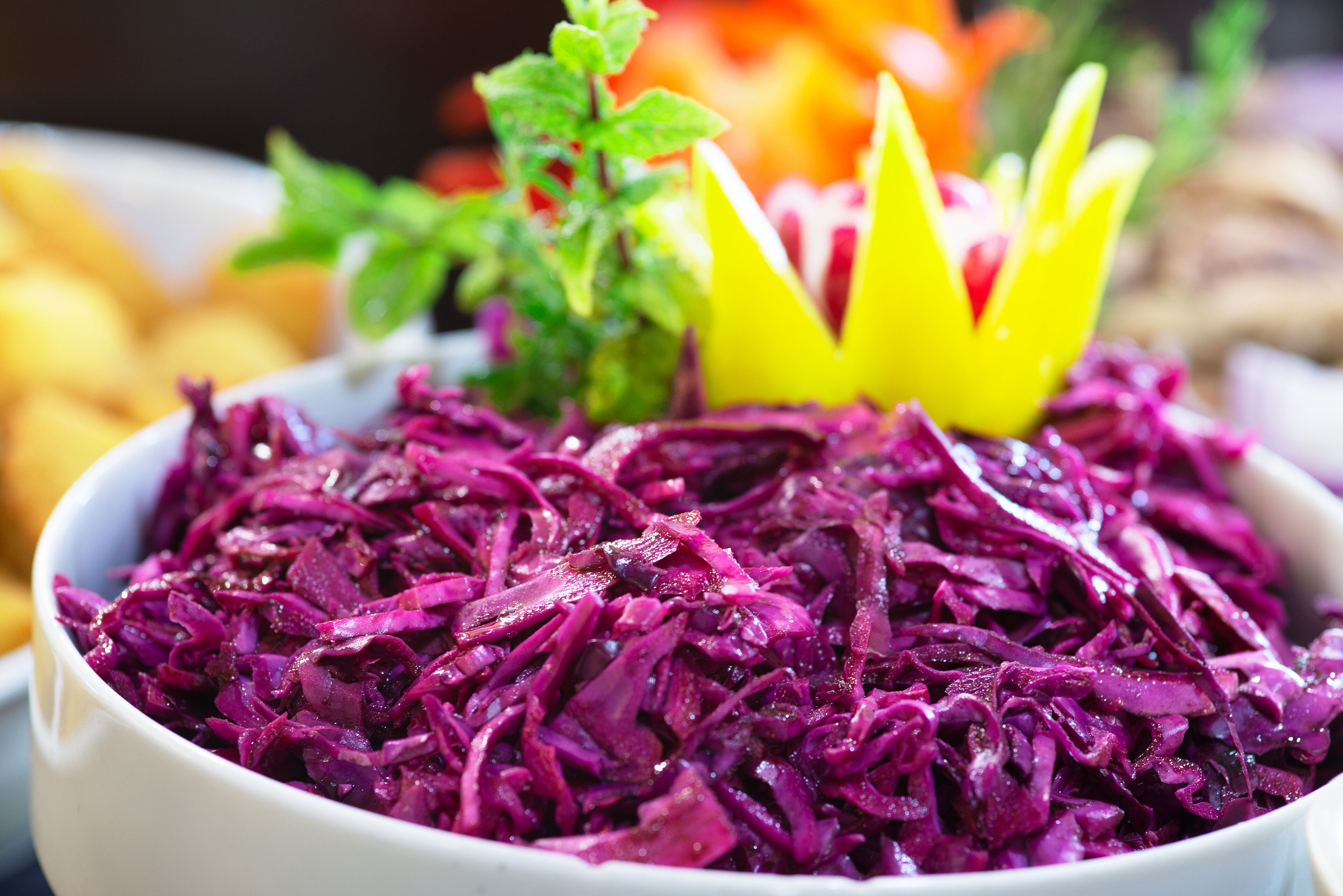 Un saladier de salade de chou rouge, orné d’une fleur jaune décorative sur le dessus.