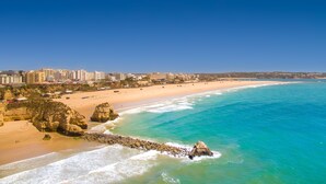 A coastal cityscape with a sandy beach, rocky outcrops, and a clear blue sea. - RR Club  Amarilis (Portimão)