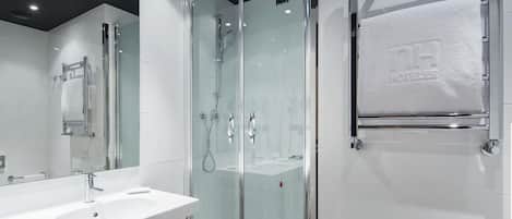 Un baño moderno con cabina de ducha de vidrio, tocador doble y perchero.