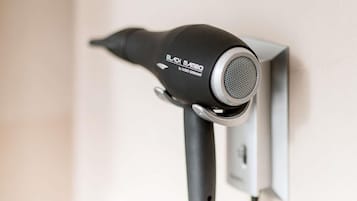 Secador de cabelo preto fixado na parede, com tomada.