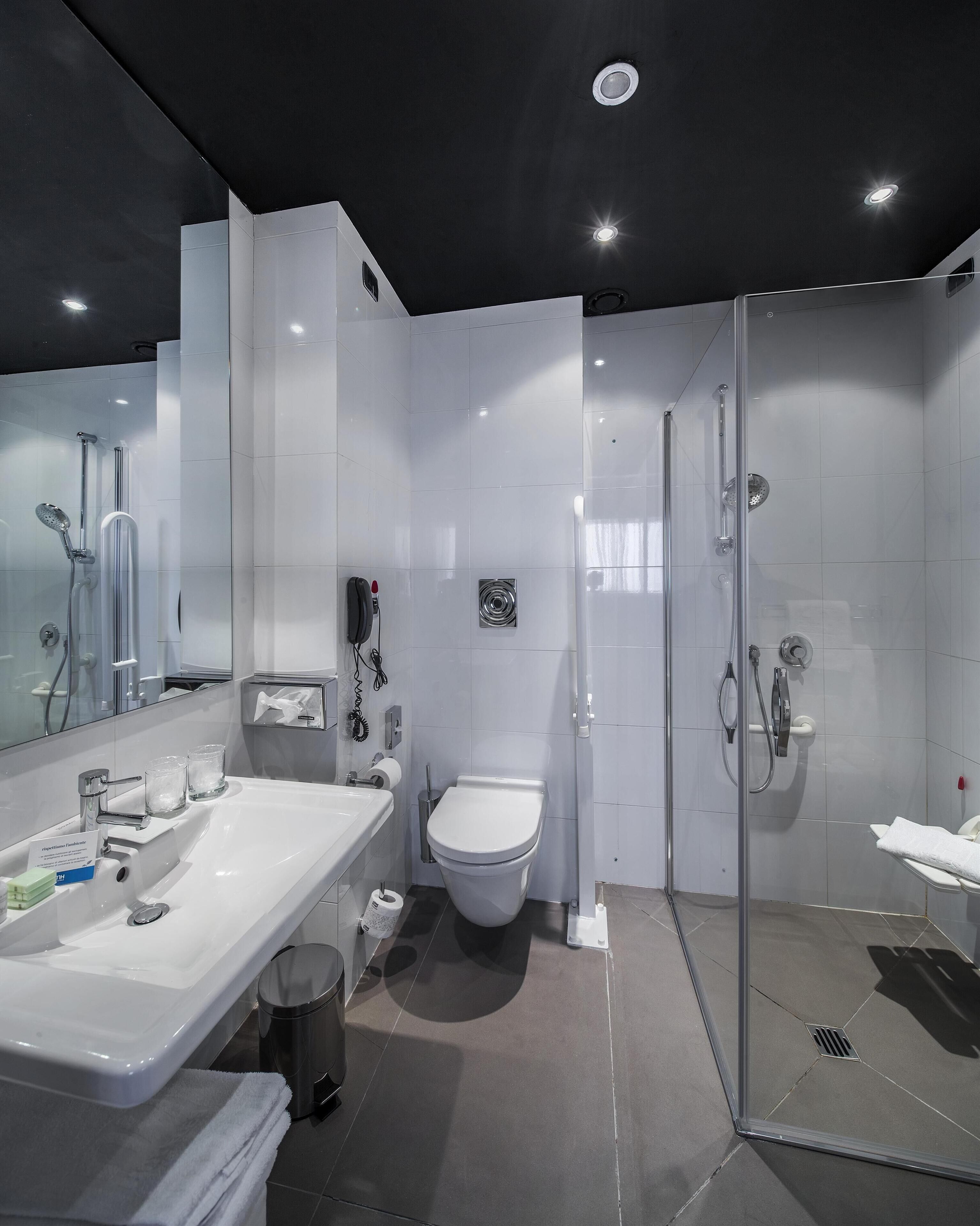A modern bathroom with a glass-enclosed shower, a white sink with a mirror, and a toilet.