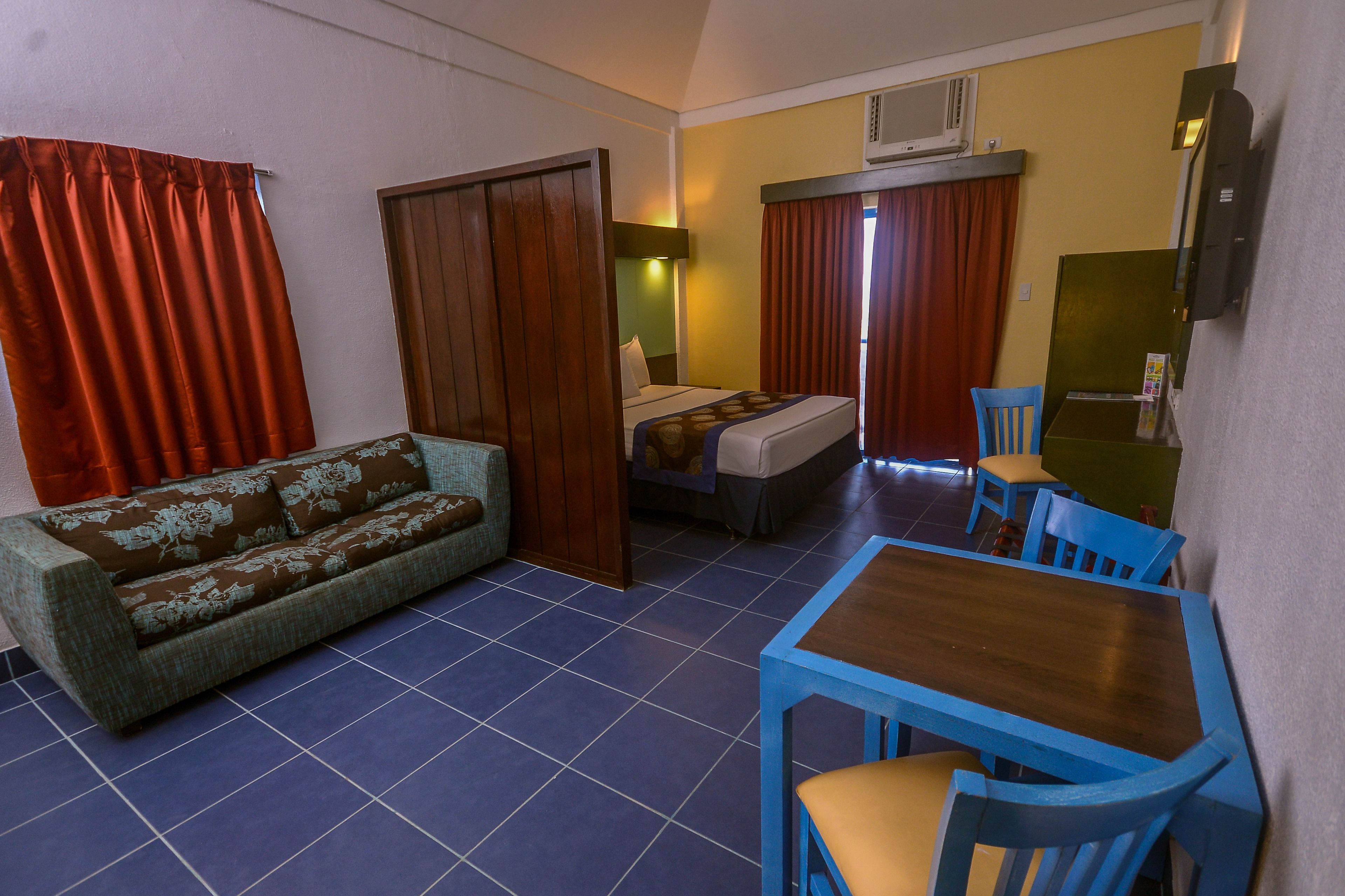 Una habitación de hotel con sofá, cama, mesa y sillas.