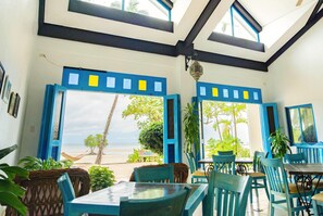Une pièce avec vue sur la plage, comprenant une table et des chaises, un luminaire suspendu et un panneau indiquant l’emplacement.