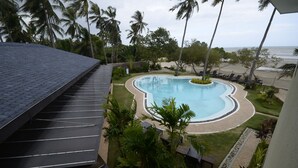 A swimming pool surrounded by palm trees and a beach view.