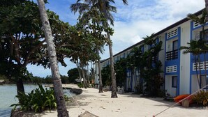 A beachside hotel with a hammock, palm trees, and a view of the water.