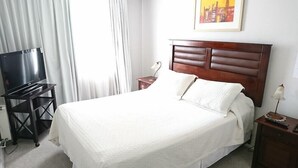 Een hotelkamer met een bed, een televisie, een bureau en een schilderij aan de muur.