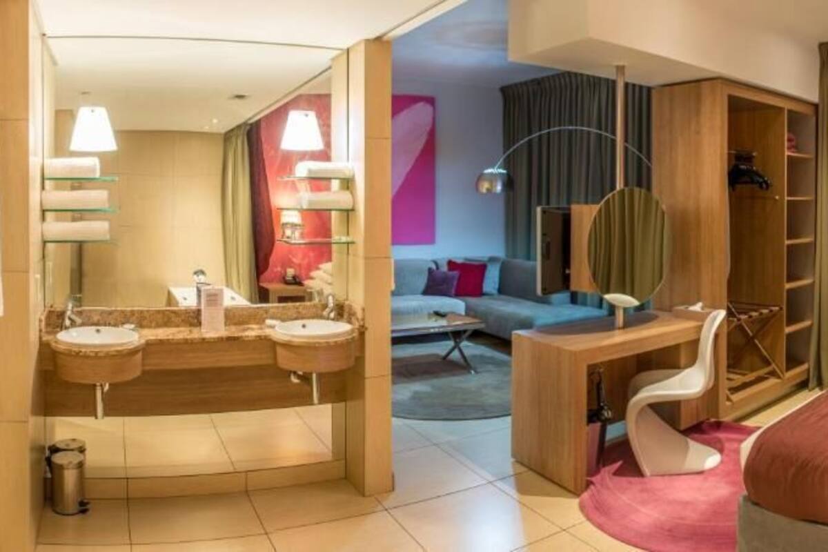 A hotel room with a bathroom, a desk, a chair, a bed, and a wardrobe.