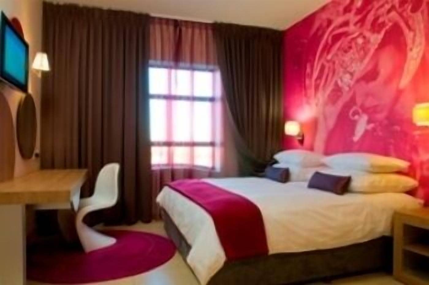 Una habitación de hotel con cama, escritorio, silla y televisor.