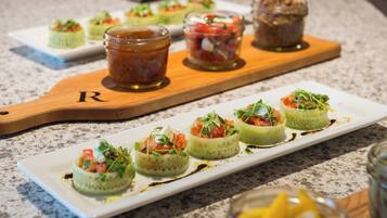 A variety of appetizers on a white rectangular plate, with a wooden board in the background.