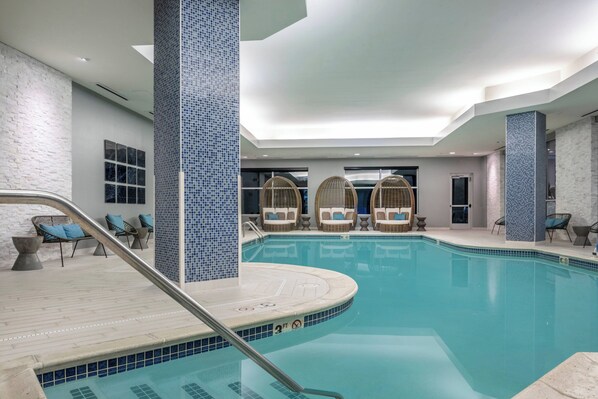 An indoor swimming pool with a tiled floor, lounge chairs, and a clear pool area. - Renaissance by Marriott Boston Patriot Place Hotel (Foxborough)