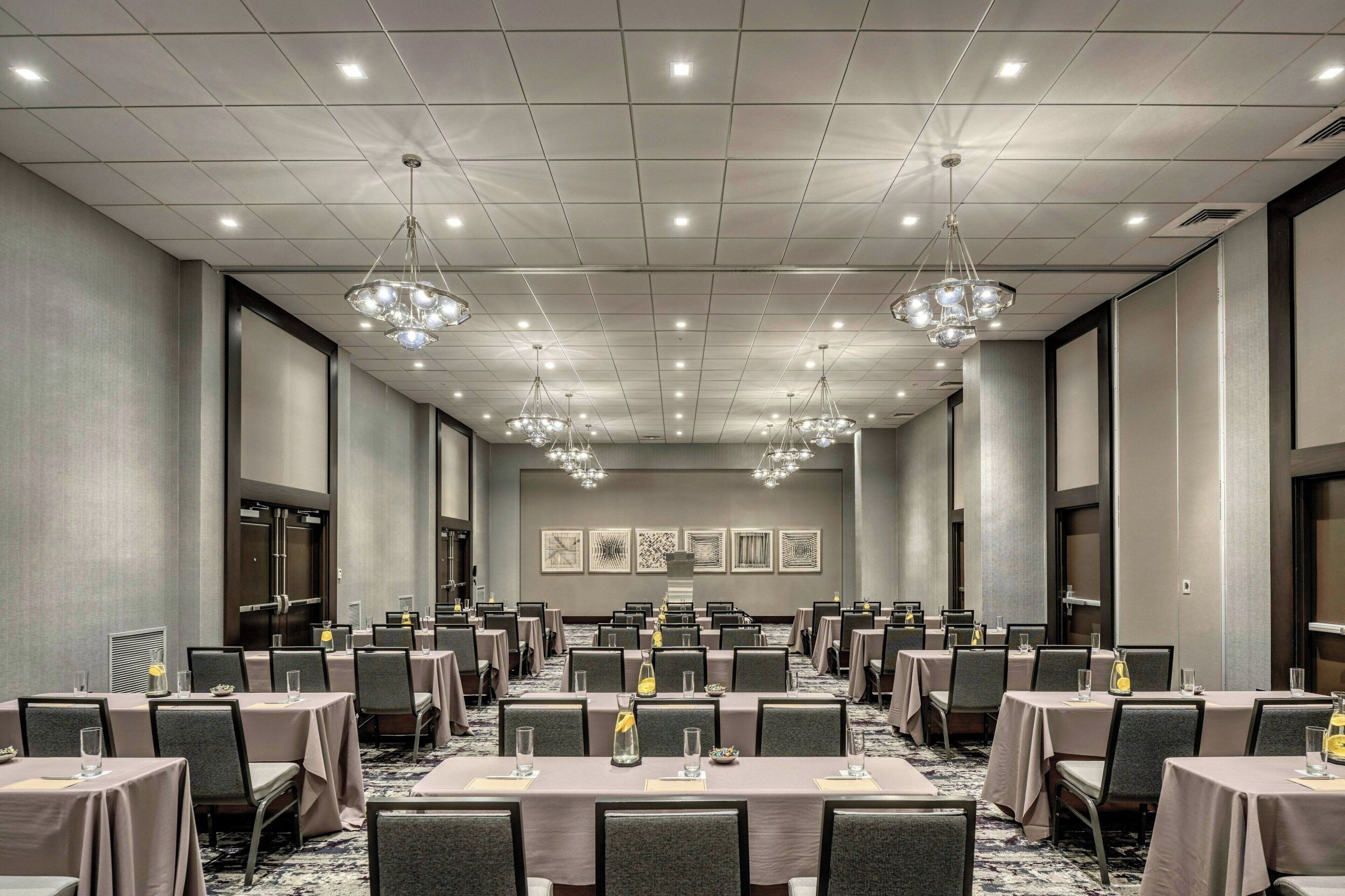 A conference room with tables, chairs, and chandeliers.