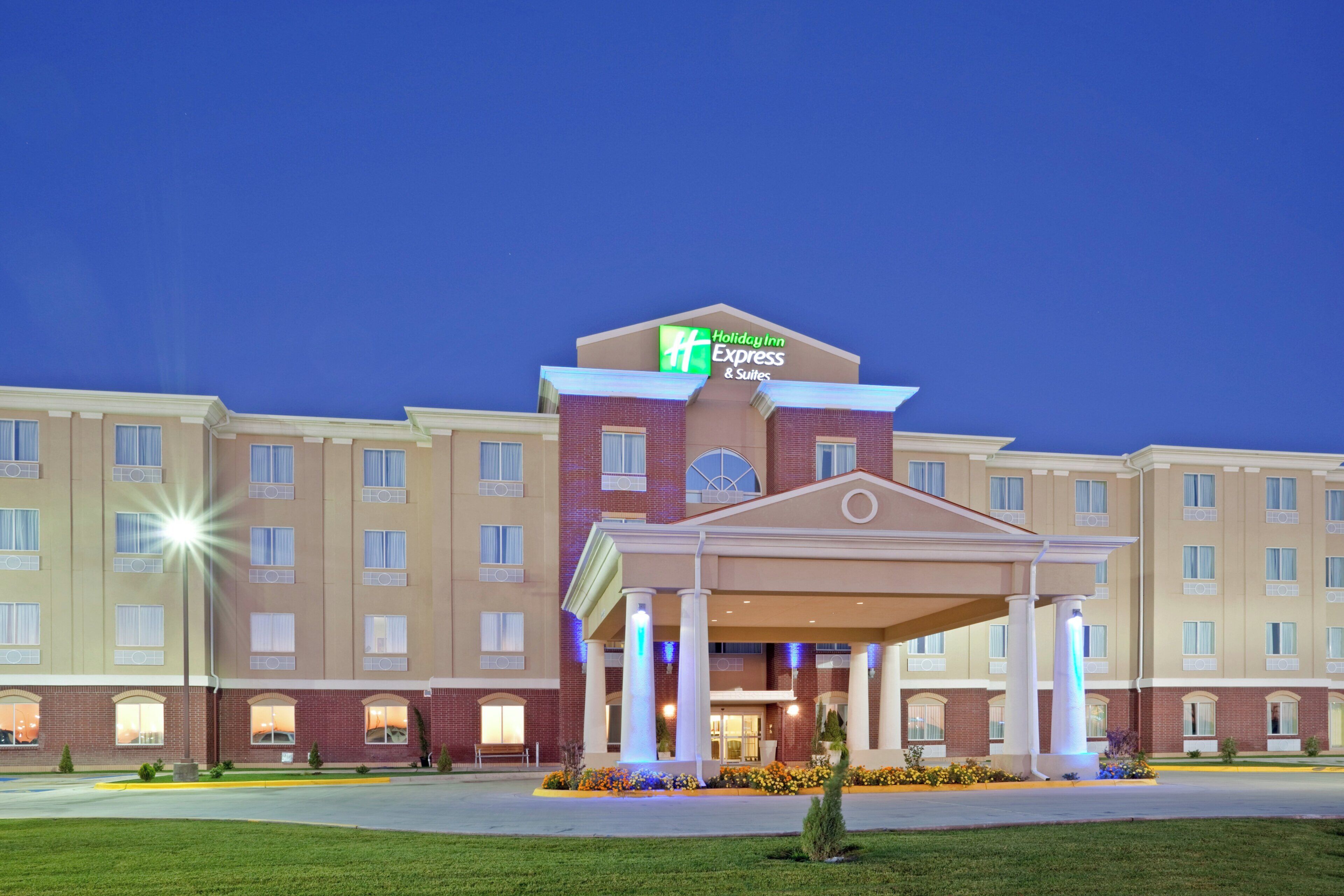 A Holiday Inn Express & Suites hotel with a central entrance, multiple windows, and a well-maintained lawn.