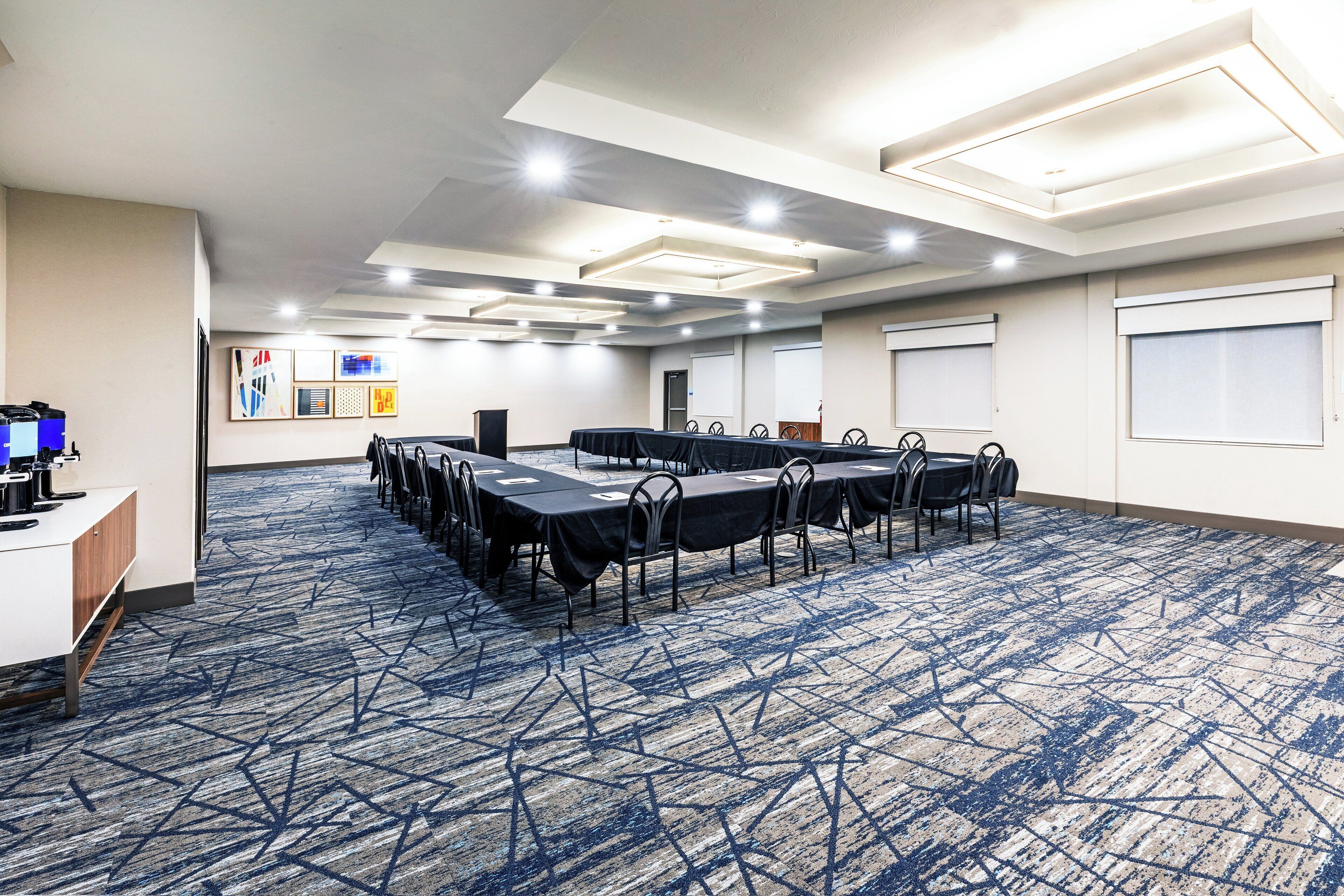 A conference room with a long table, chairs, a podium, and a presentation screen.