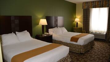 A hotel room with two beds, a nightstand with a lamp, a telephone, and a window with curtains.