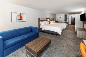 A hotel room with a large bed, a blue sofa, a wooden coffee table, and a TV. - Holiday Inn Express Hotel & Suites Dumas by IHG (Dumas)