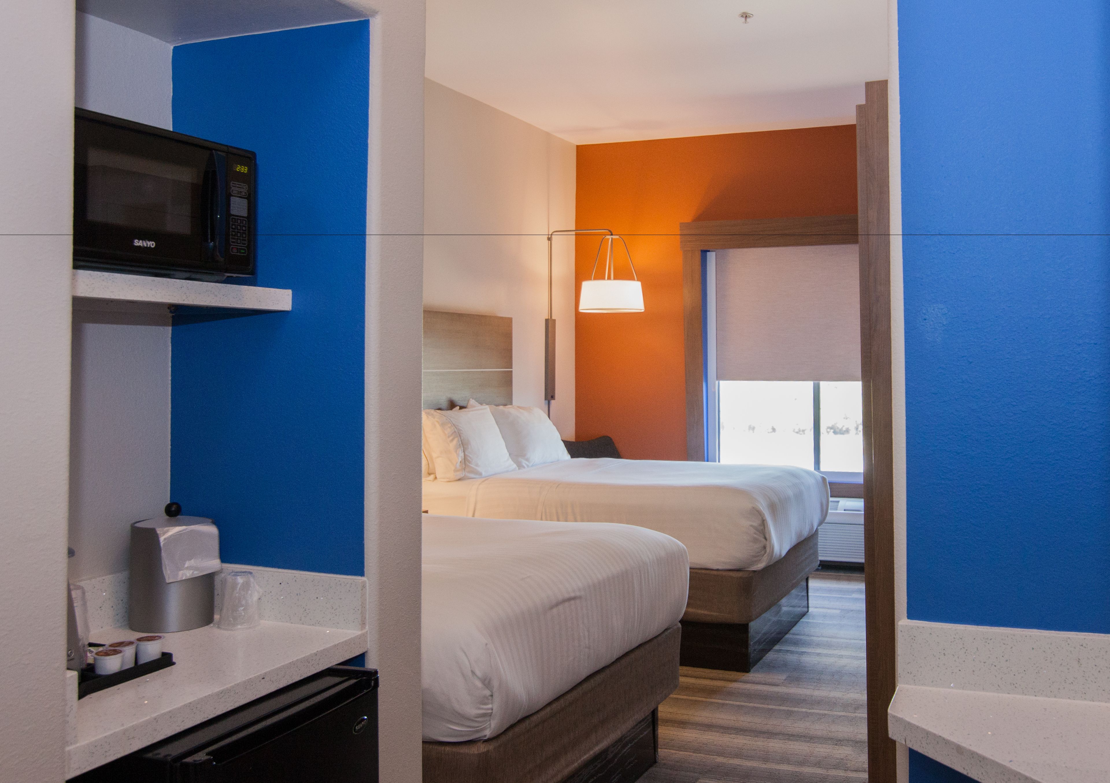 Une chambre d’hôtel avec deux lits, un four à micro-ondes, une machine à café et une lampe de chevet.