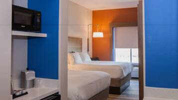 Une chambre d’hôtel avec deux lits, un four à micro-ondes, une machine à café et une lampe de chevet.