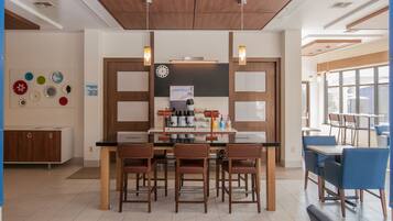 A modern kitchen with a central island, bar stools, and a dining area with blue chairs.