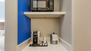 A kitchenette with a microwave, coffee maker, and a paper towel dispenser.