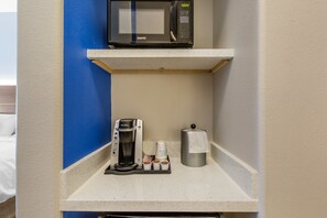 A kitchenette with a microwave, coffee maker, and a paper towel dispenser.