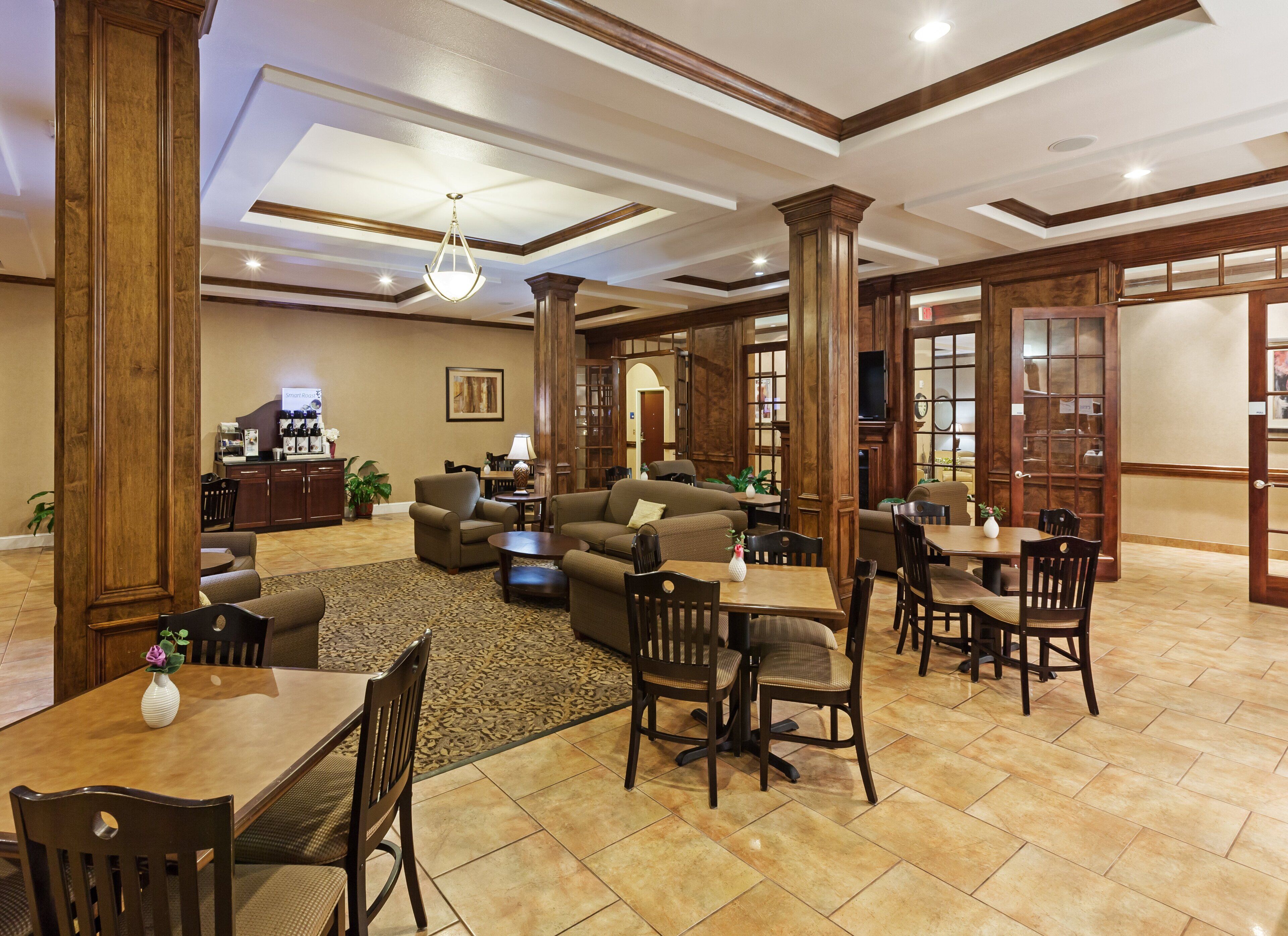 A spacious hotel lobby with a seating area, a coffee station, and a television.