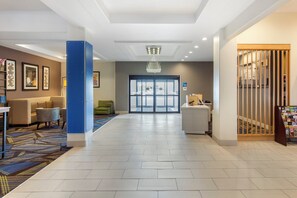 A hotel lobby with a reception desk, seating area, and a large glass door entrance. - Holiday Inn Express Hotel & Suites Houston-Alvin by IHG (Alvin)