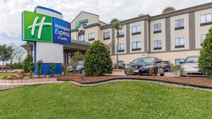 A Holiday Inn Express & Suites building with a sign, parking lot, and landscaping.