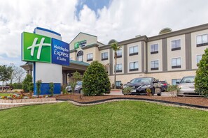 A Holiday Inn Express & Suites building with a sign, parking lot, and landscaping.