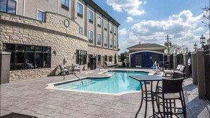 A hotel with a swimming pool, outdoor seating, and a stone facade.
