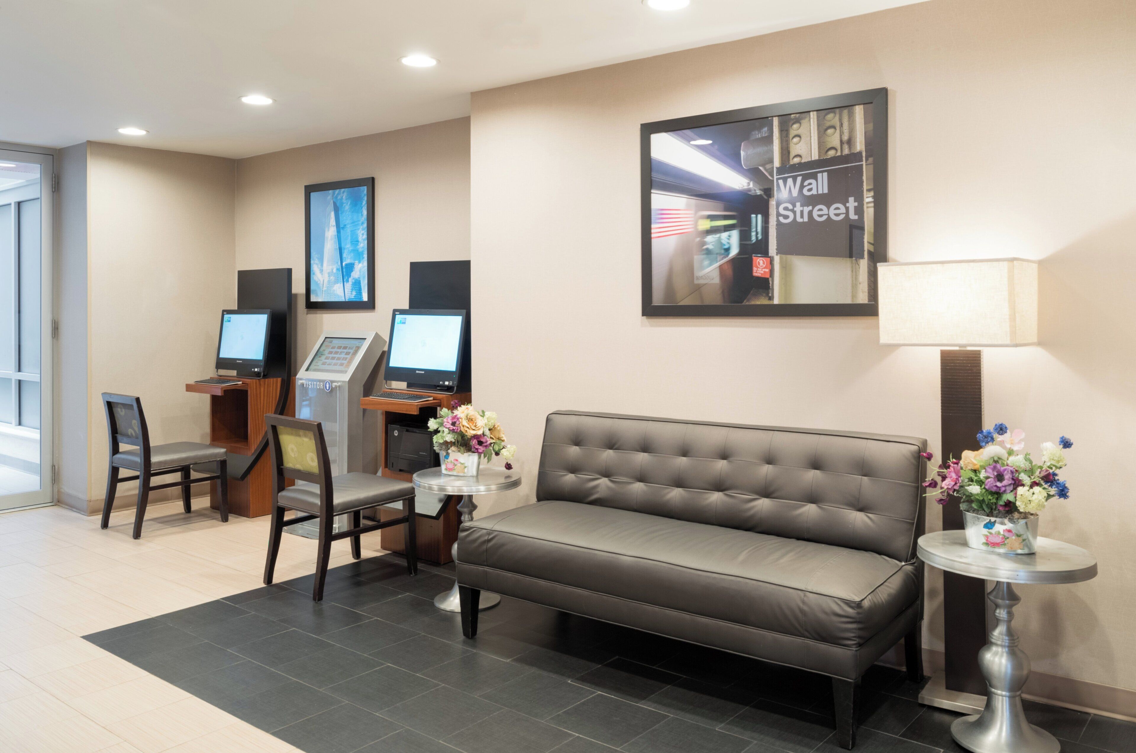 Un hall d’hôtel avec un comptoir d’accueil, des ordinateurs, un canapé et une lampe.